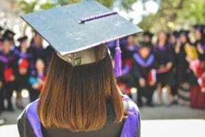 A graduate picture from the back. There is a moment in a purple gown with a black On and purple castle